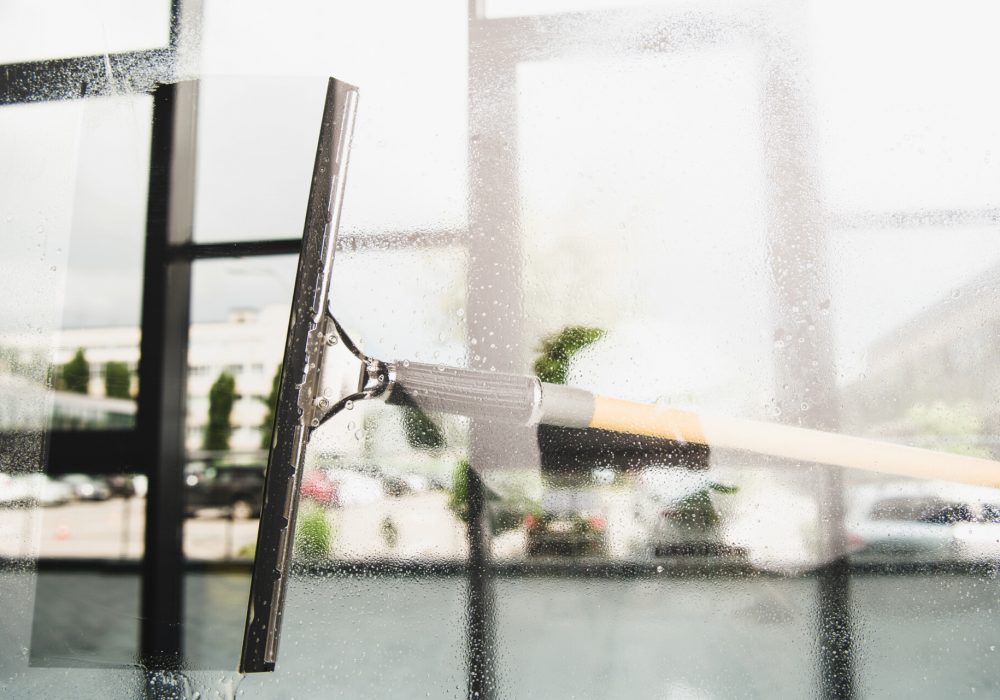 close-up view of cleaning and wiping window with squeegee